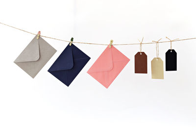 Envelopes with luggage tags hanging on clothesline against white background