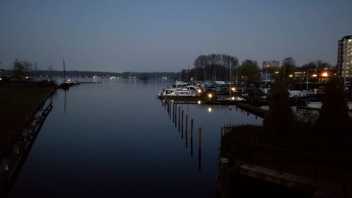 Boats moored at harbor against clear sky at night