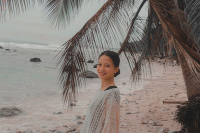 Portrait of young woman standing at beach