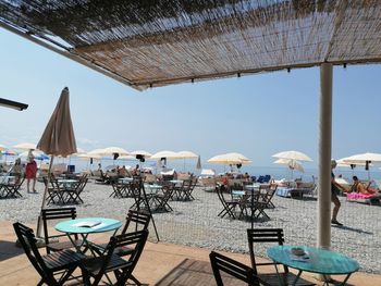 Chairs and tables at beach against clear sky