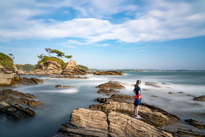 High angle view of teenage girl standing on rock by sea