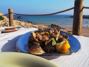 Close-up of breakfast on table by sea against sky