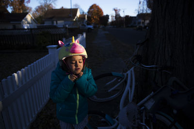 Close-up of girl standing by fence on ground