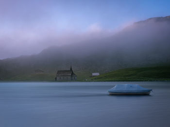 Boat in lake by building against sky