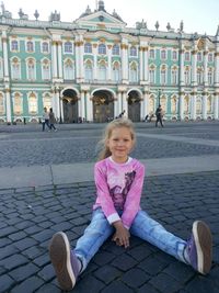 Portrait of smiling girl sitting in front of building