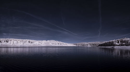 Scenic view of lake by snowcapped mountains against sky at night