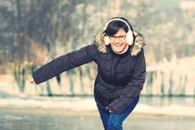 Portrait of smiling young woman wearing ear muff and fur coat during winter