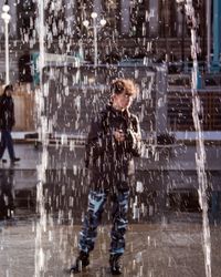 Teenage boy standing by fountain