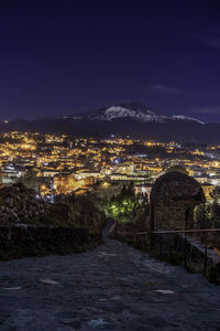 Illuminated buildings in town against sky at night