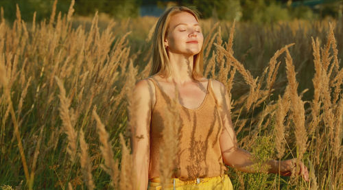 Portrait of young woman standing amidst plants