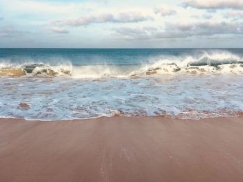 Scenic view of beach against cloudy sky