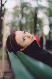 Thoughtful woman reclining on bench at park