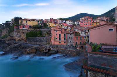 Houses by river in town against sky