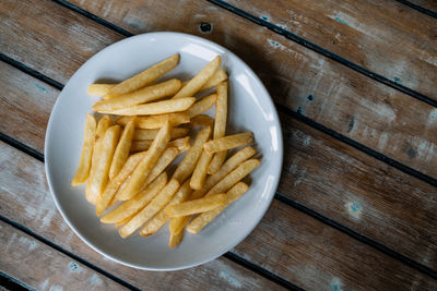 High angle view of meat and fries in plate on table