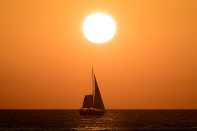 Silhouette sailboat sailing on sea against sky during sunset