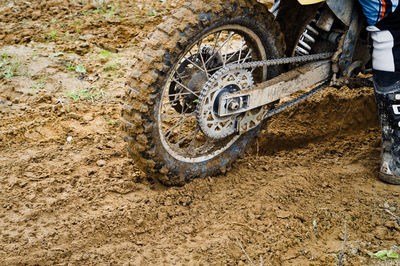 Low section of person riding motorcycle on dirt road