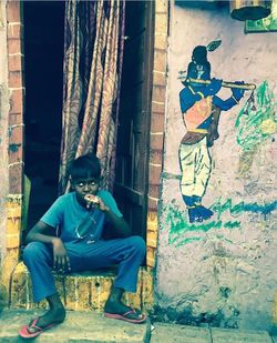 Portrait of young man sitting on wall