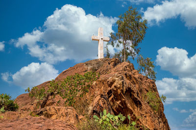 Low angle view of cross on rock against sky