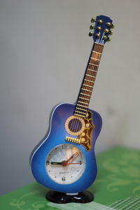 Close-up of toy guitar clock against gray background