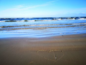 Heart shape on beach against sky