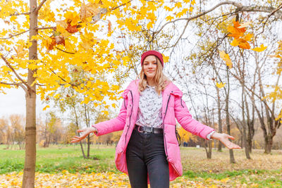 Full length of a smiling woman standing in autumn