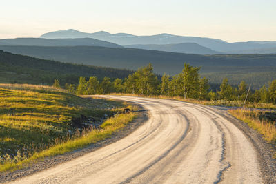 Scenic view of road by mountains against sky
