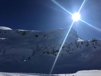 Scenic view of snowcapped mountains against sky on sunny day