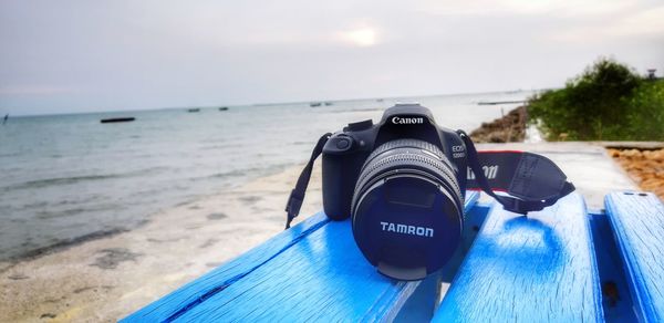 Close-up of camera on beach against sky