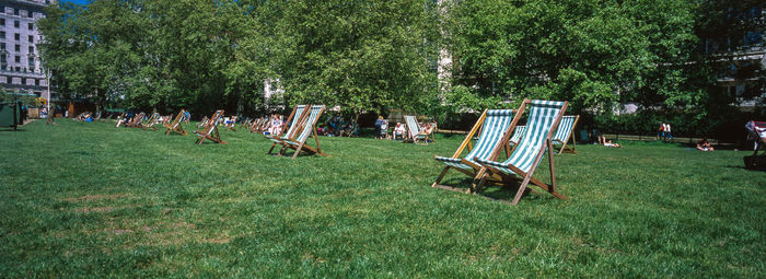 Panoramic view of deck chairs on field in public park