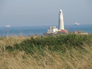 Lighthouse by sea against sky