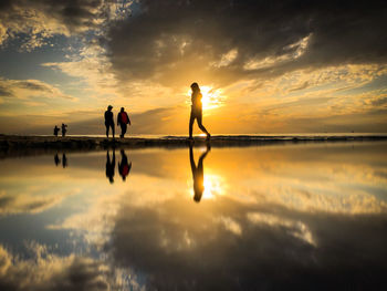 Silhouette people standing against sky during sunset