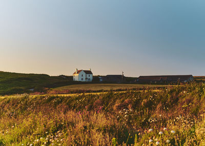 House on field against sky at sunset