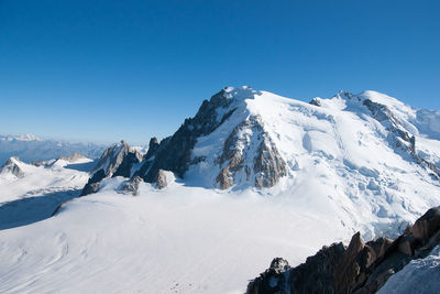 Scenic view of snow covered mountains against clear blue sky