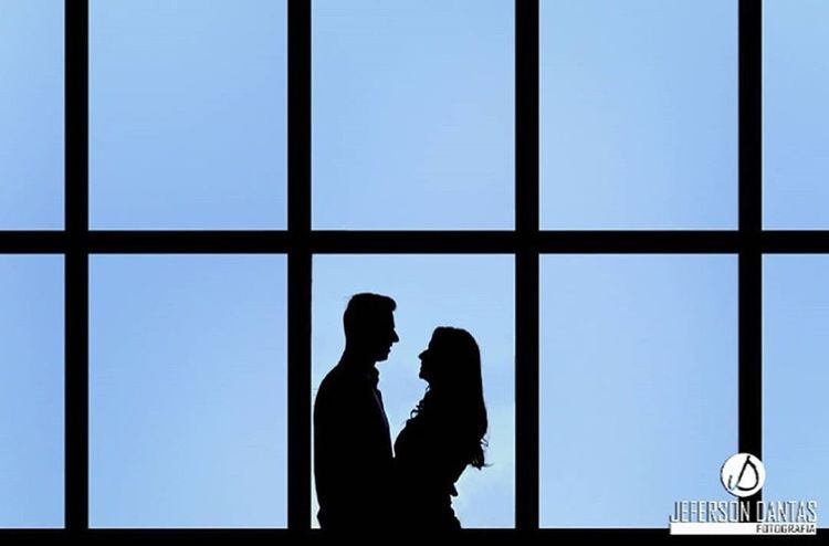 SILHOUETTE OF COUPLE STANDING AGAINST SKY SEEN THROUGH WINDOW