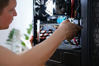 Man repairs a computer system unit, changes parts, video card and hard drive