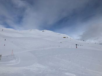 People skiing on snow covered mountain against sky