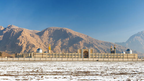 Scenic view of building by mountains against sky