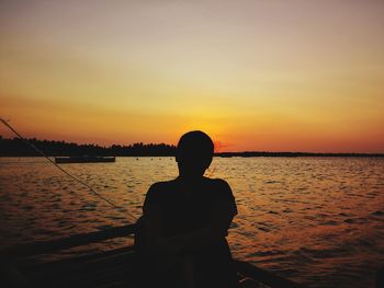 Silhouette man looking at sea against sky during sunset