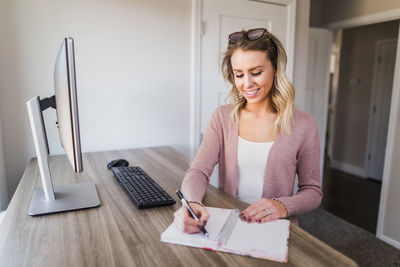 Woman using phone while sitting on table at home