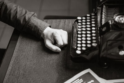 High angle view of male author resting hand at desk by antique typewriter