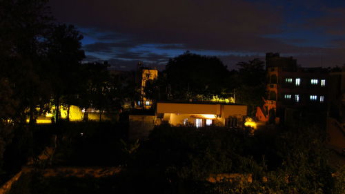 High section of illuminated town against cloudy sky at night