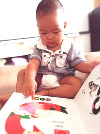 Close-up of boy playing with book on bed at home