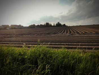 View of field against cloudy sky