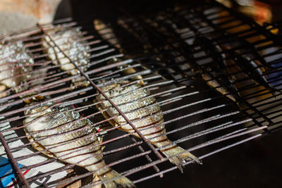 Delicious dried fish placed in rows on metal grill on counter at local seafood market in countryside