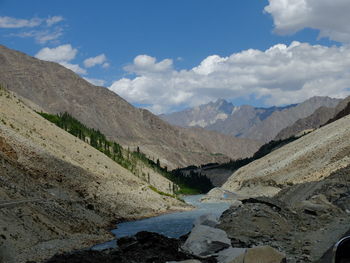 Scenic view of river by mountains against sky