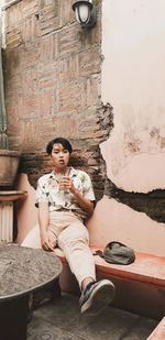 Portrait of woman sitting against broken wall