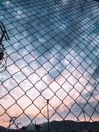 Full frame shot of chainlink fence against sky during sunset