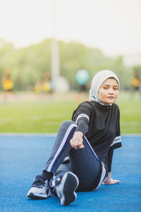 Thoughtful female athlete stretching at stadium