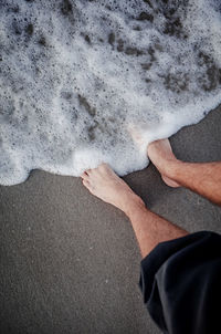 Low section of person standing at beach