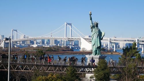 Statue of liberty replica and bridge against sky